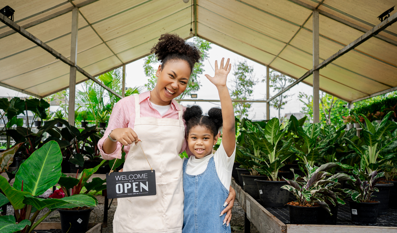 A small business owner with her daughter holding an open sign
